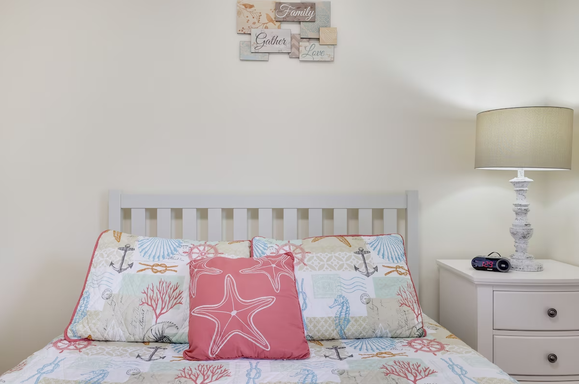 A bedroom with a bed , nightstand and lamp