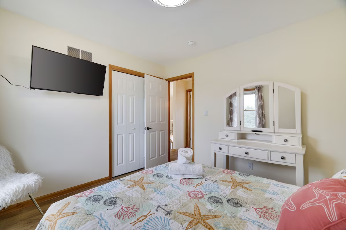 A bedroom with a bed , dresser , television and mirror.