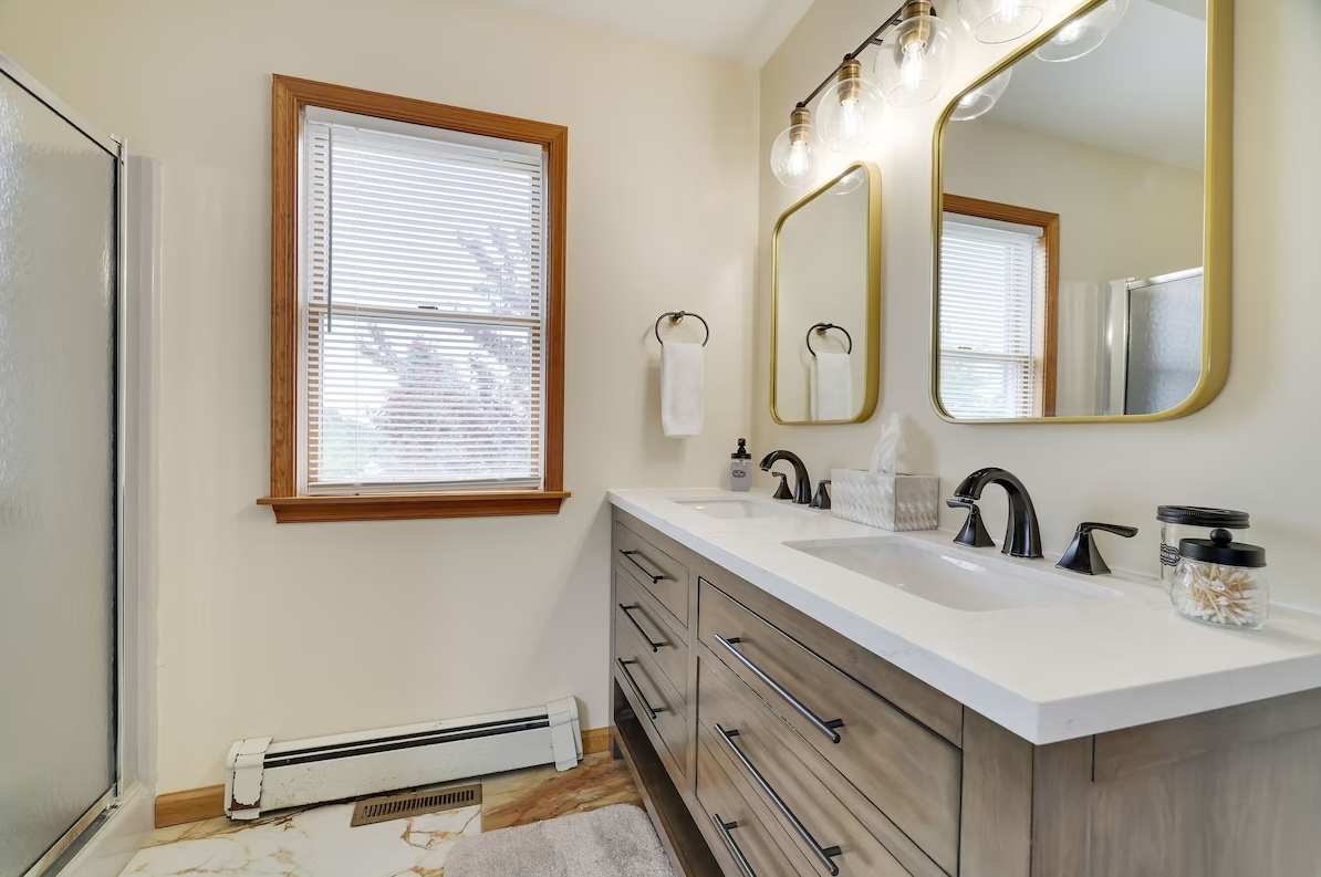 A bathroom with two sinks , a mirror and a window.