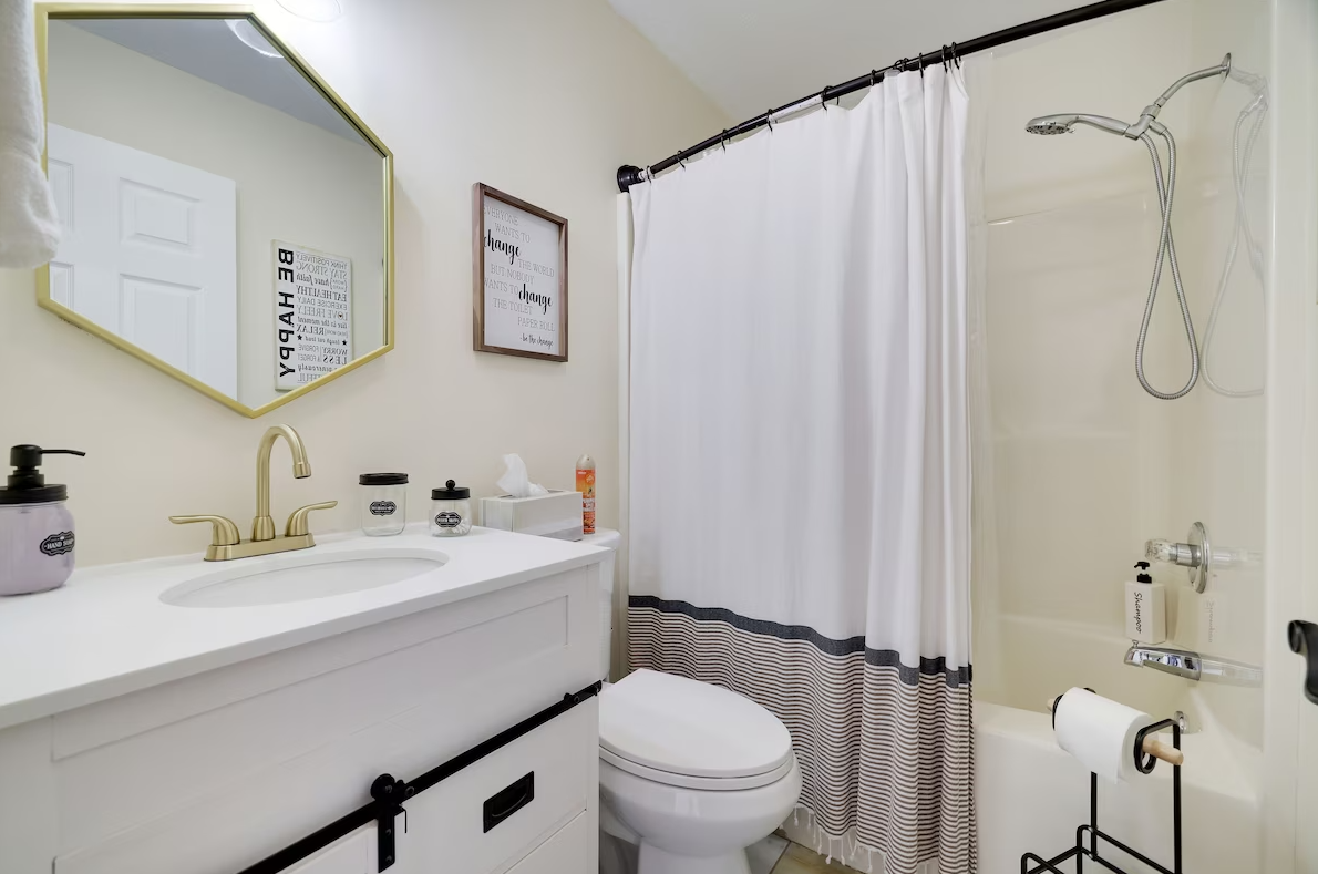 A bathroom with a toilet , sink , shower and mirror.