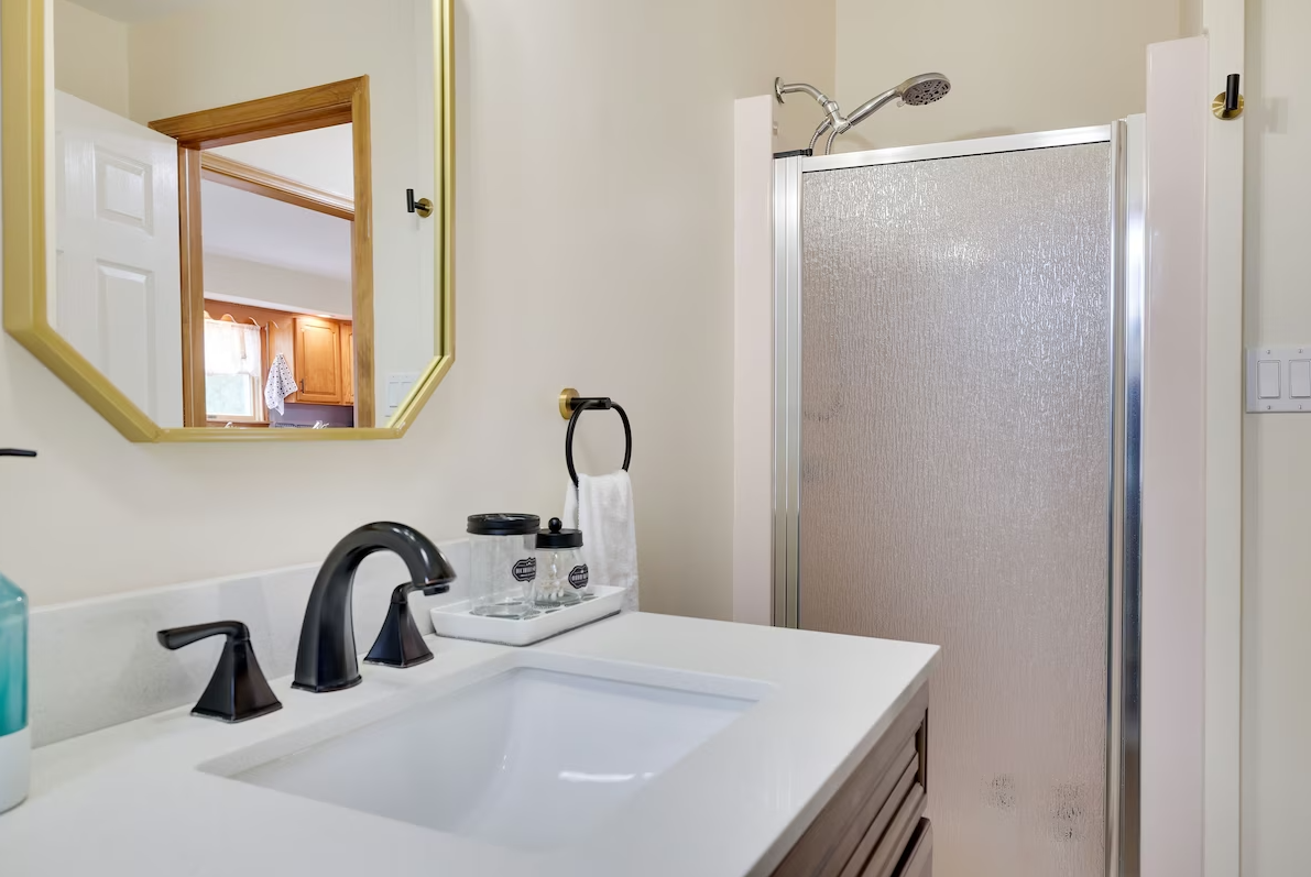 A bathroom with a sink , mirror and shower.