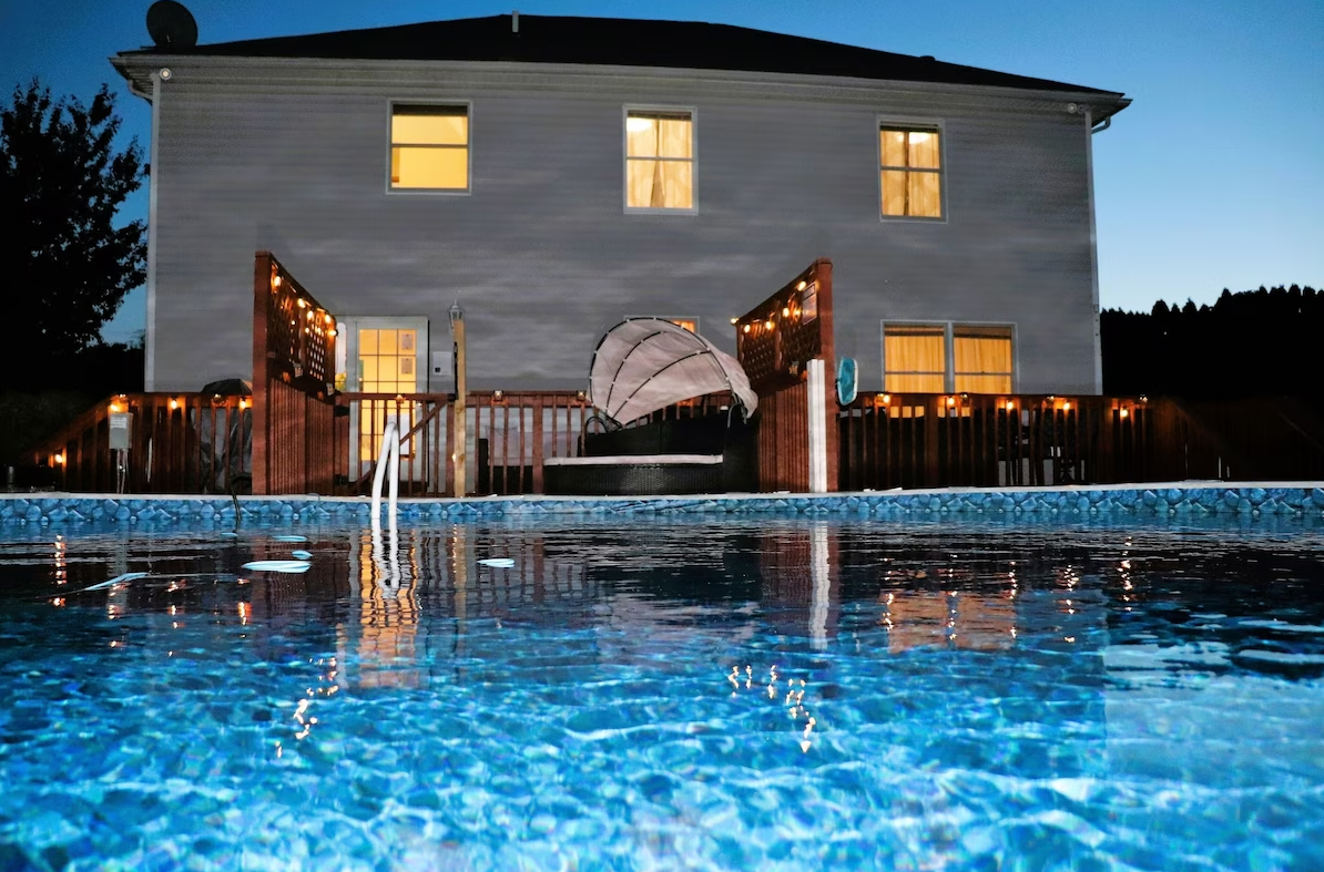 A large house with a swimming pool in front of it at night.