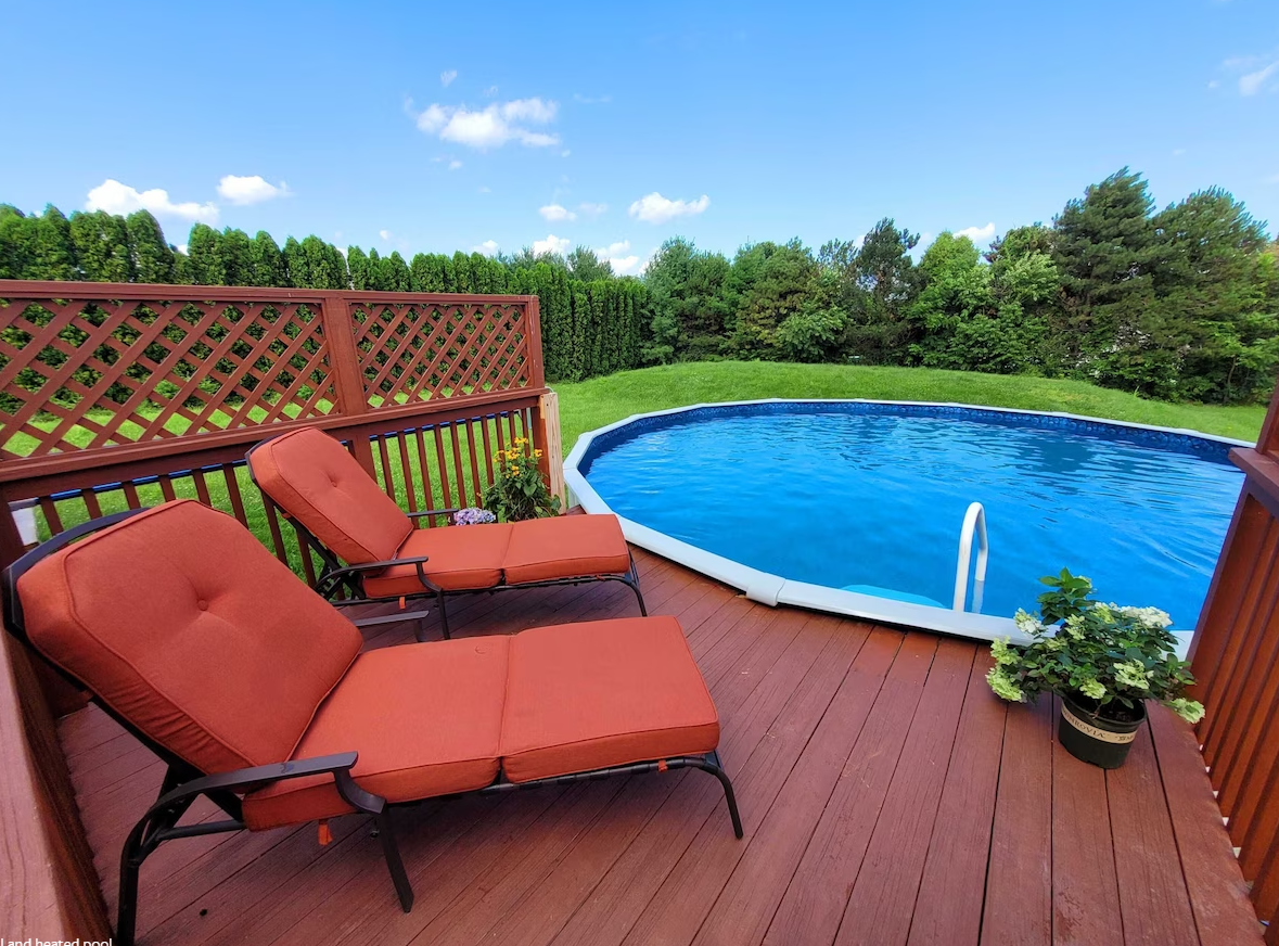 A deck with chairs and a swimming pool in the background
