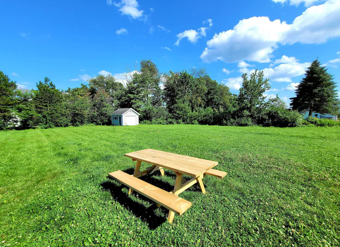 A wooden picnic table is sitting in the middle of a lush green field.