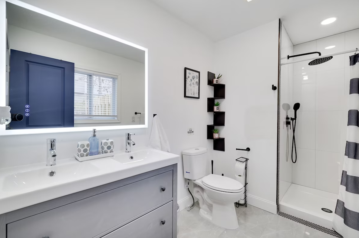 A bathroom with a toilet , sink , mirror and shower.
