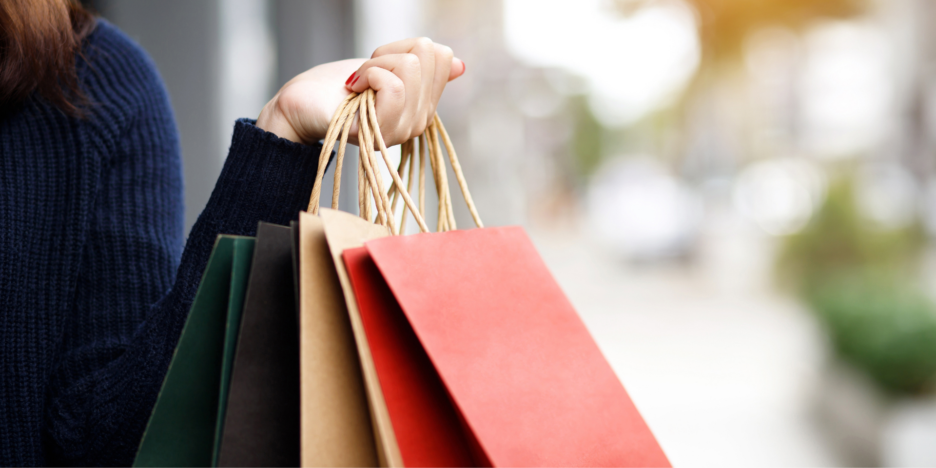 A woman is holding a bunch of shopping bags in her hand.
