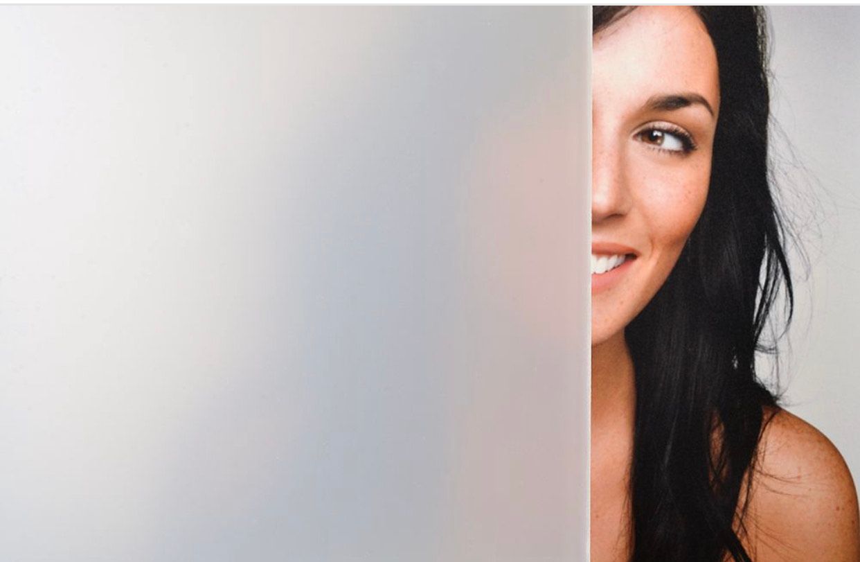 Woman peeking from behind a frosted glass panel, smiling