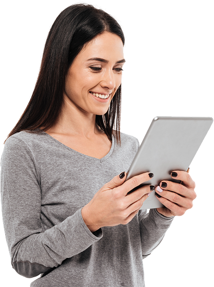 Woman smiling, looking at a tablet, holding it with both hands. She wears a gray sweater.