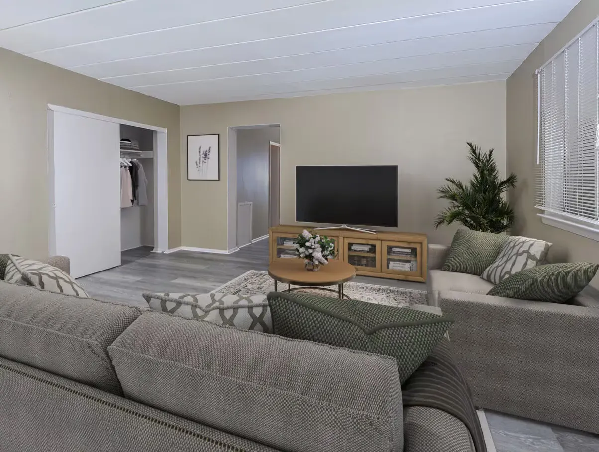 Spacious gray living room with sectional sofa, TV, wooden coffee table, and white blinds.