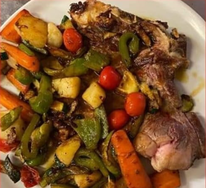 Piatto di carne alla griglia con verdure arrostite, tra cui carote, peperoni, pomodori e zucchine.