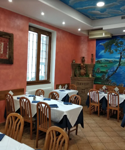 Interno del ristorante con tavoli apparecchiati per cenare, pareti color pesca, soffitto dipinto e opere d'arte alle pareti.