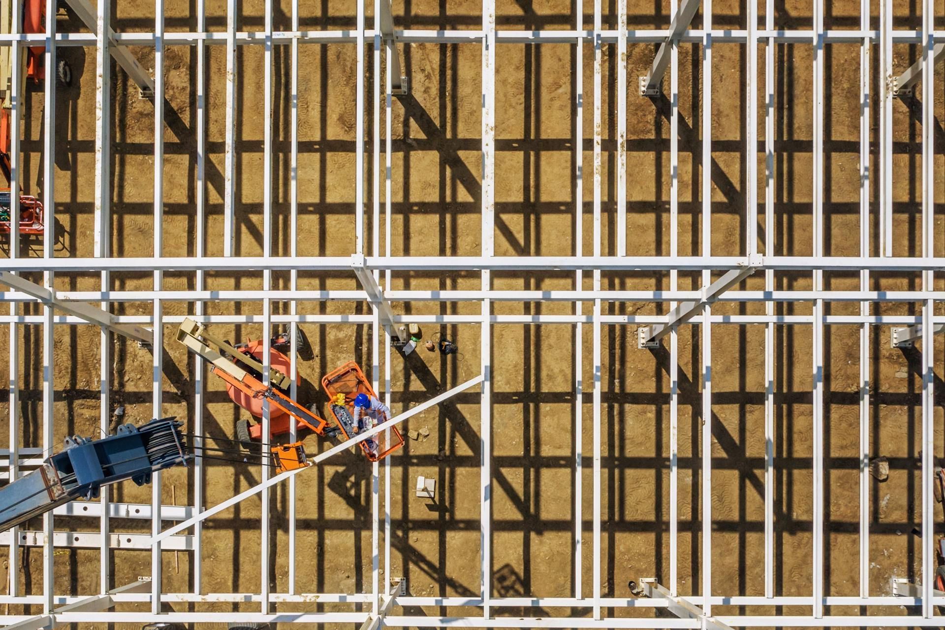 Overhead view of a construction site with steel framework and an orange lift.