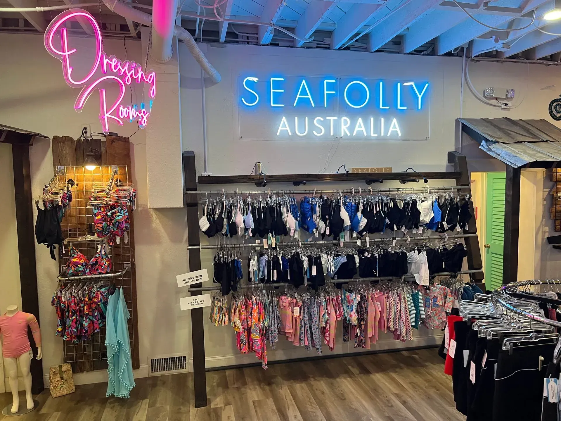 Interior of a Seafolly Australia store, featuring swimwear displayed on racks and a neon sign.