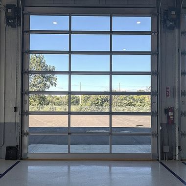 Open garage door framing a bright outdoor view with trees and blue sky