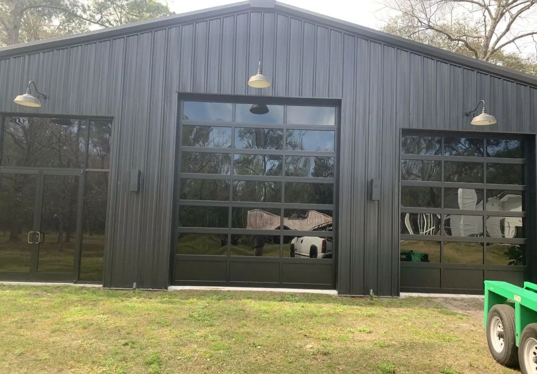 Black barn-style building with large windows and hanging lights, reflected in the glass.