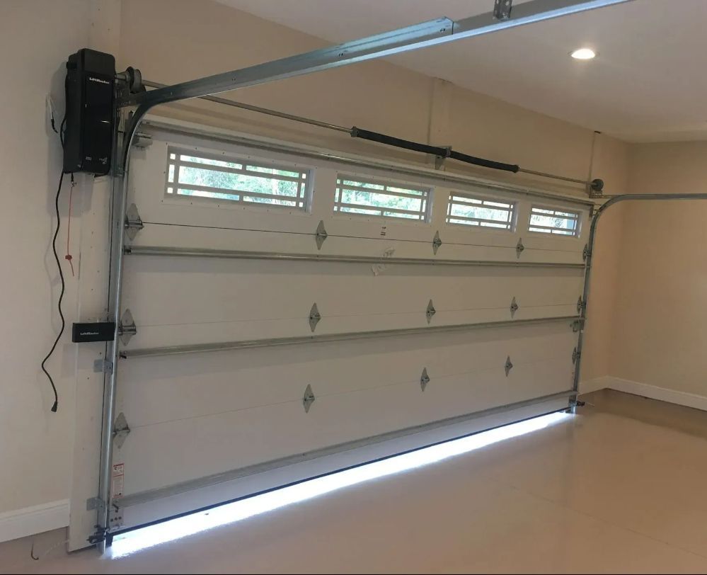 Closed white garage door with small windows and an automatic opener in a clean garage