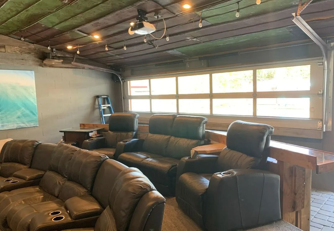 Leather recliners in a rustic room with large windows and exposed ceiling lights.