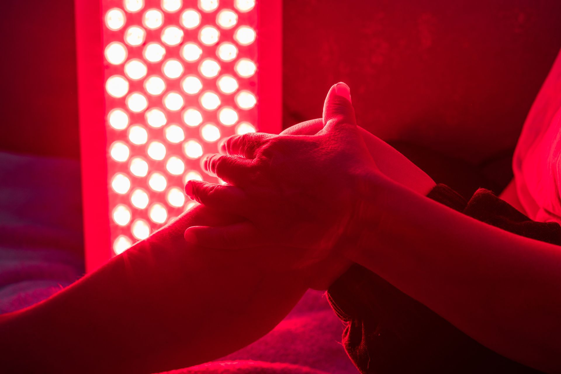 A person is holding another person 's hand in front of a red light.