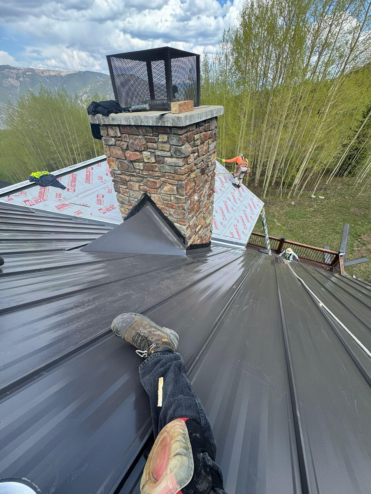 A person is laying on the roof of a house with a chimney.