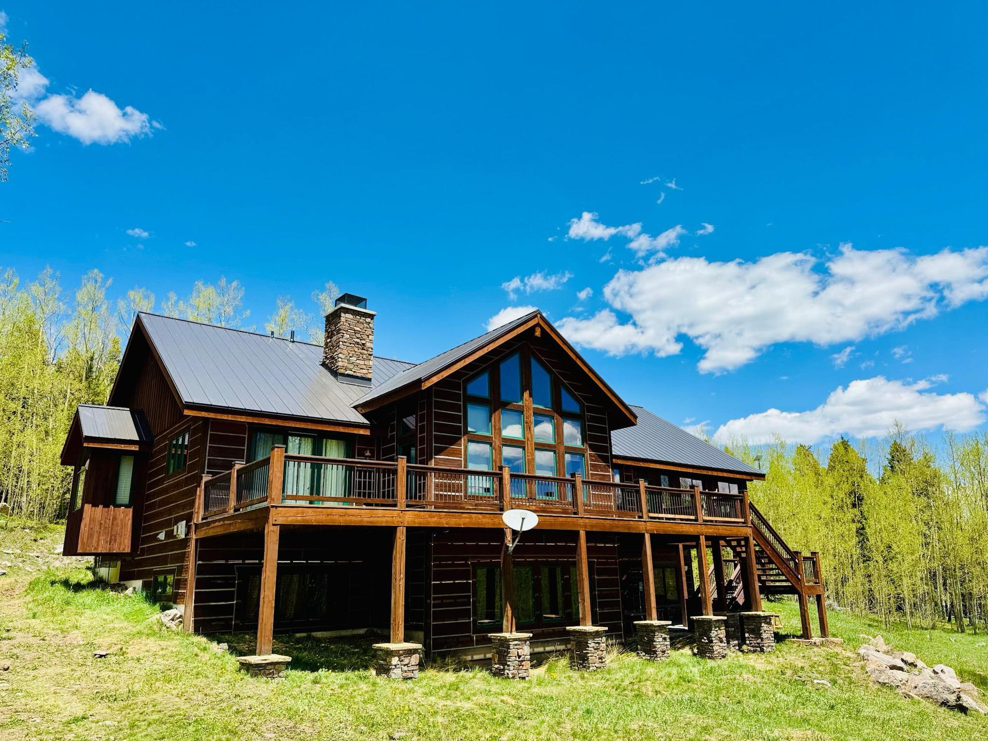 A large log cabin sits in the middle of a grassy field