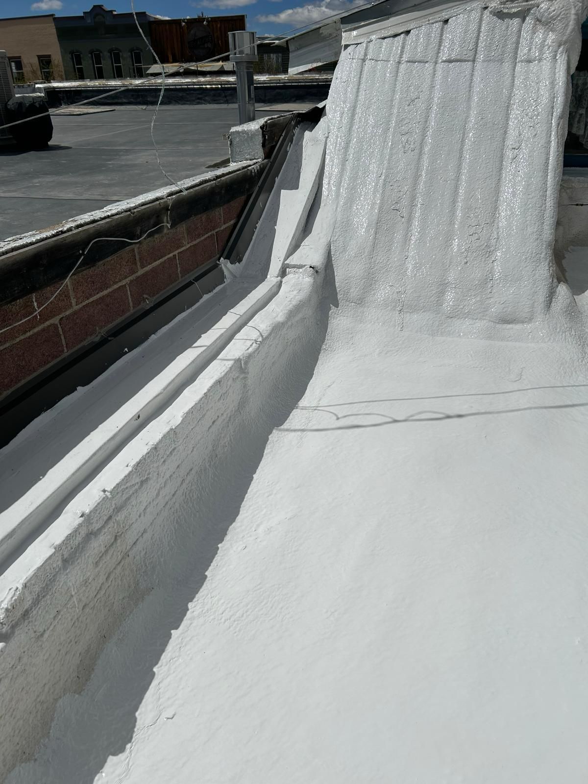 A white roof with a brick wall in the background