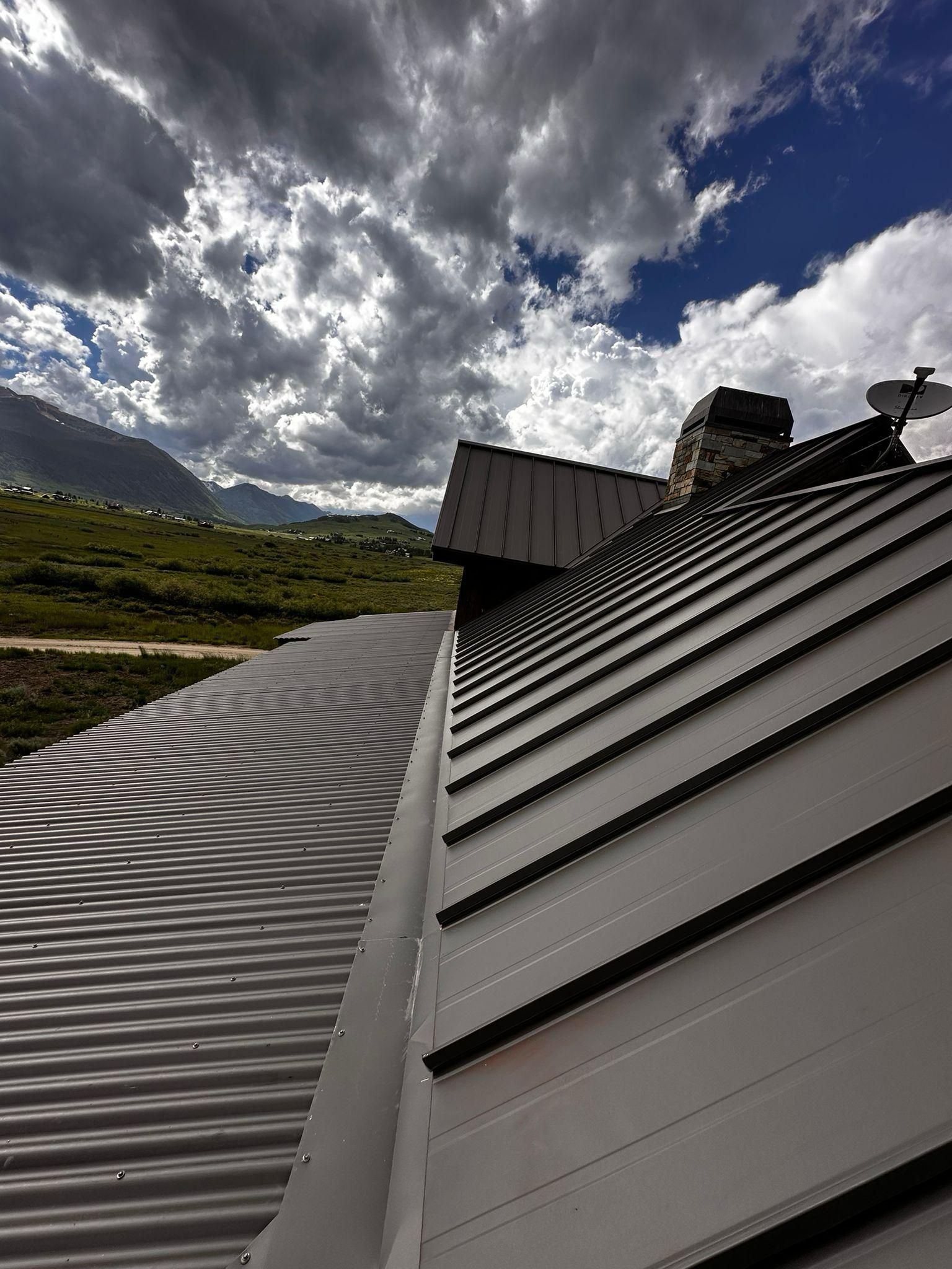 A roof with a chimney and mountains in the background