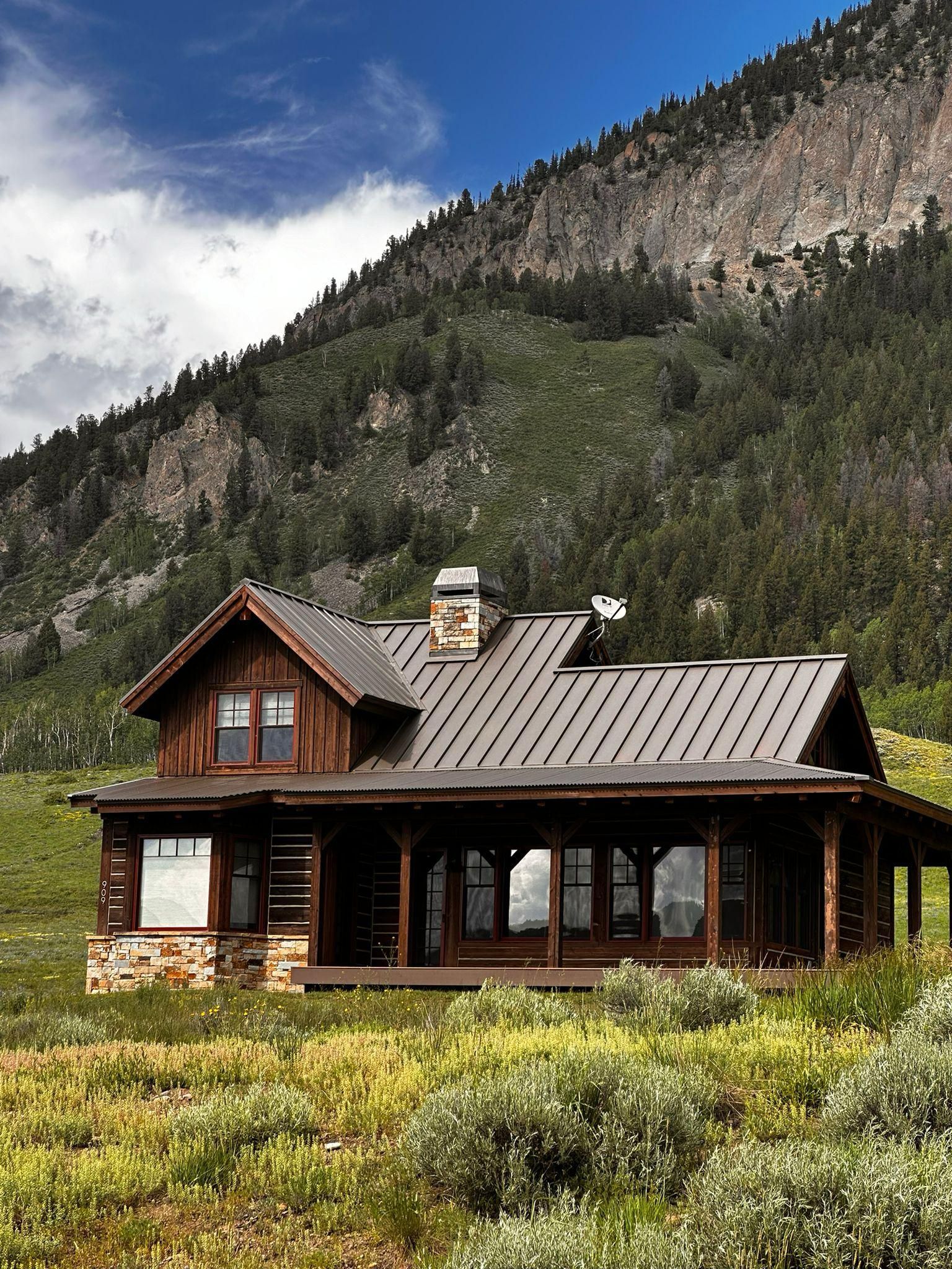 A house in the middle of a field with mountains in the background