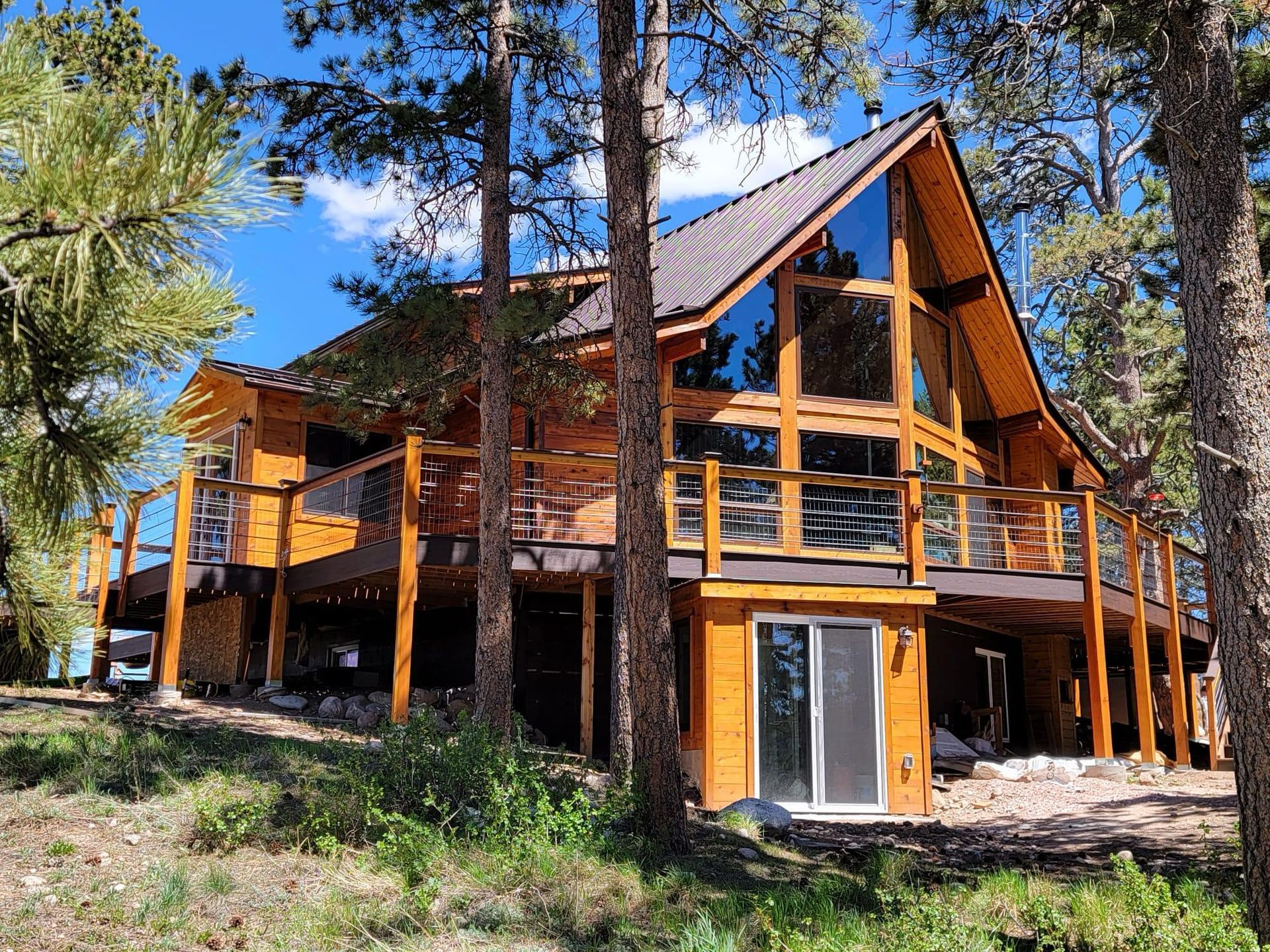 A large wooden house is surrounded by trees on a hillside