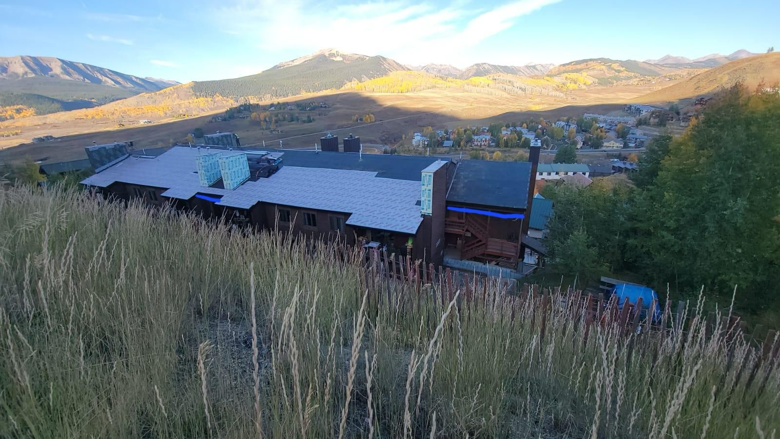 A building in the middle of a field with mountains in the background