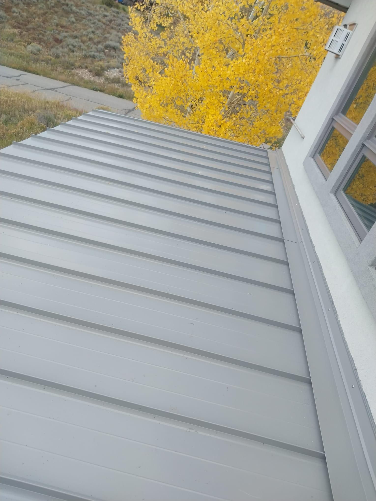 A roof with a yellow tree in the background