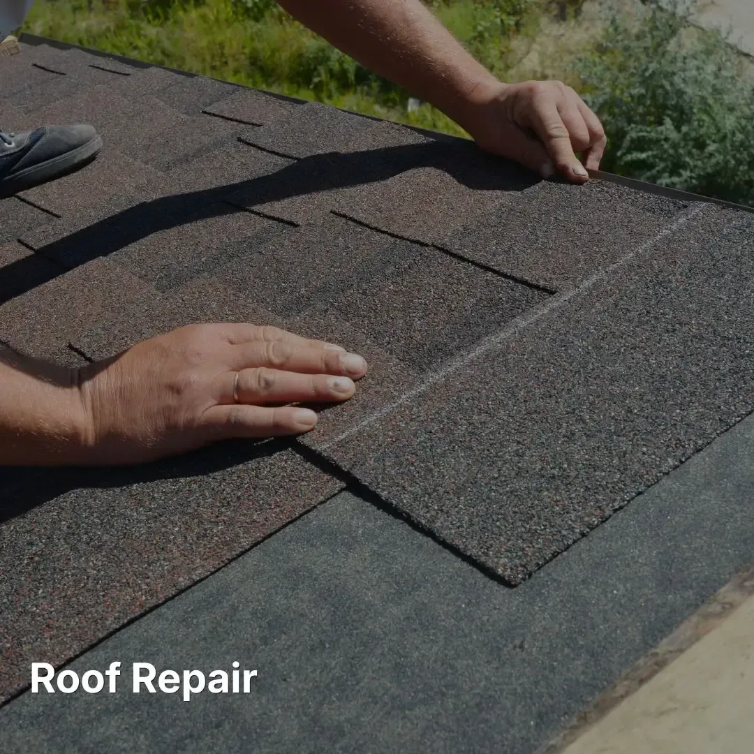 A pair of hands installs brown asphalt shingles on a roof as part of a repair.