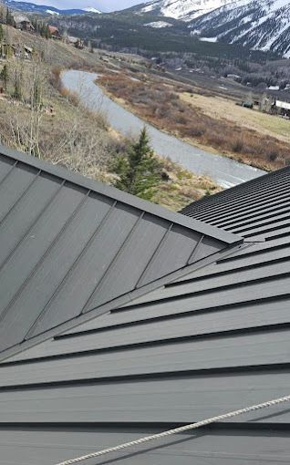 A roof with a view of a river and mountains in the background.