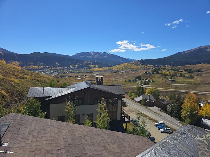 A house in the middle of a valley with mountains in the background