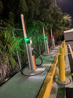 Electric vehicle charging stations with green and red lights, at night.