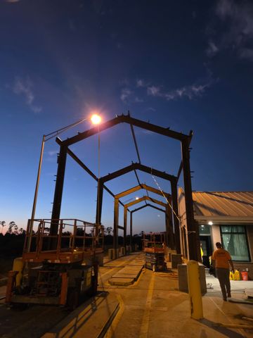 Steel frame structure against a bright blue sky with wispy clouds.