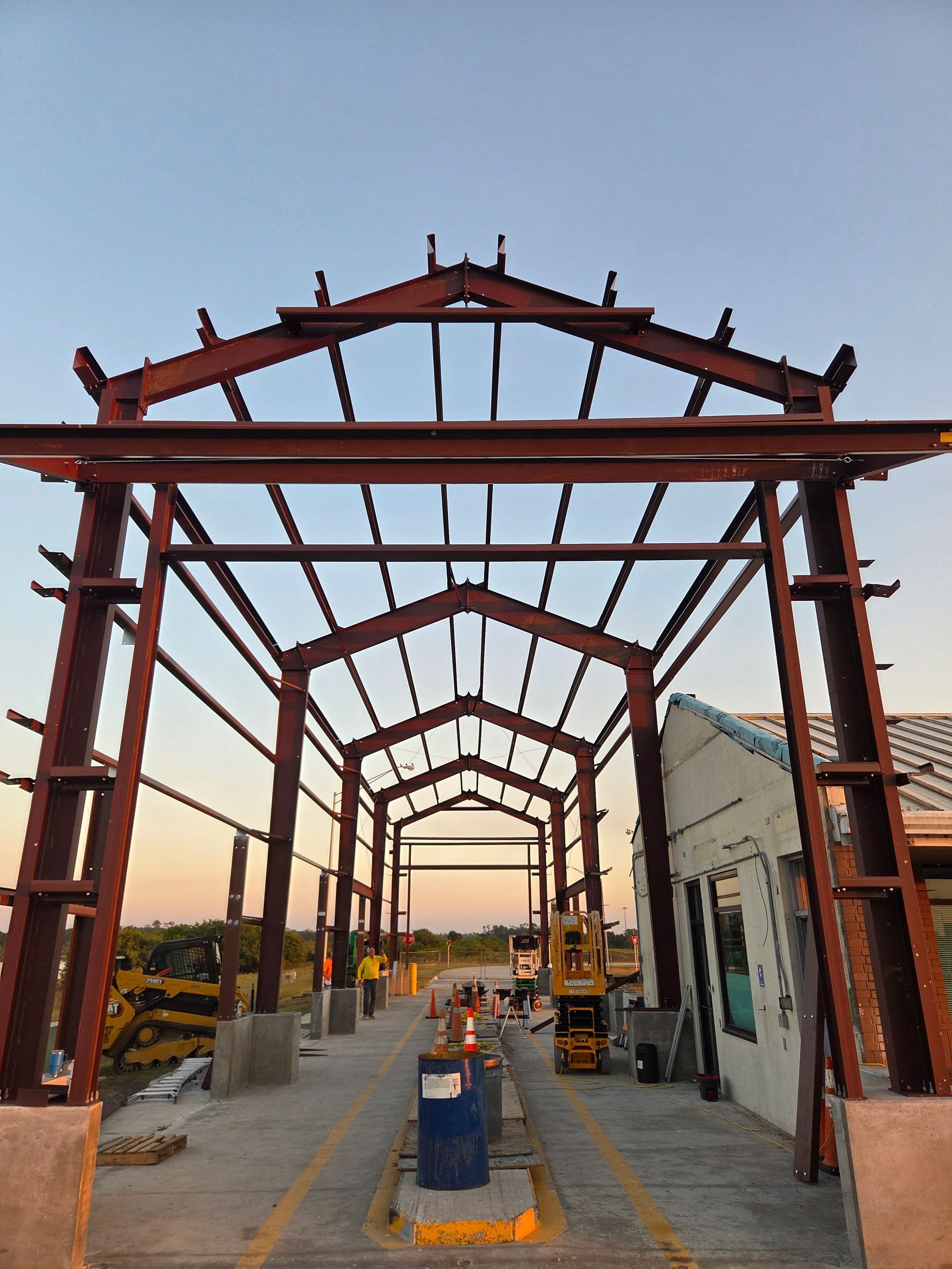 Red steel frame structure, likely an entrance or archway, under construction outdoors.