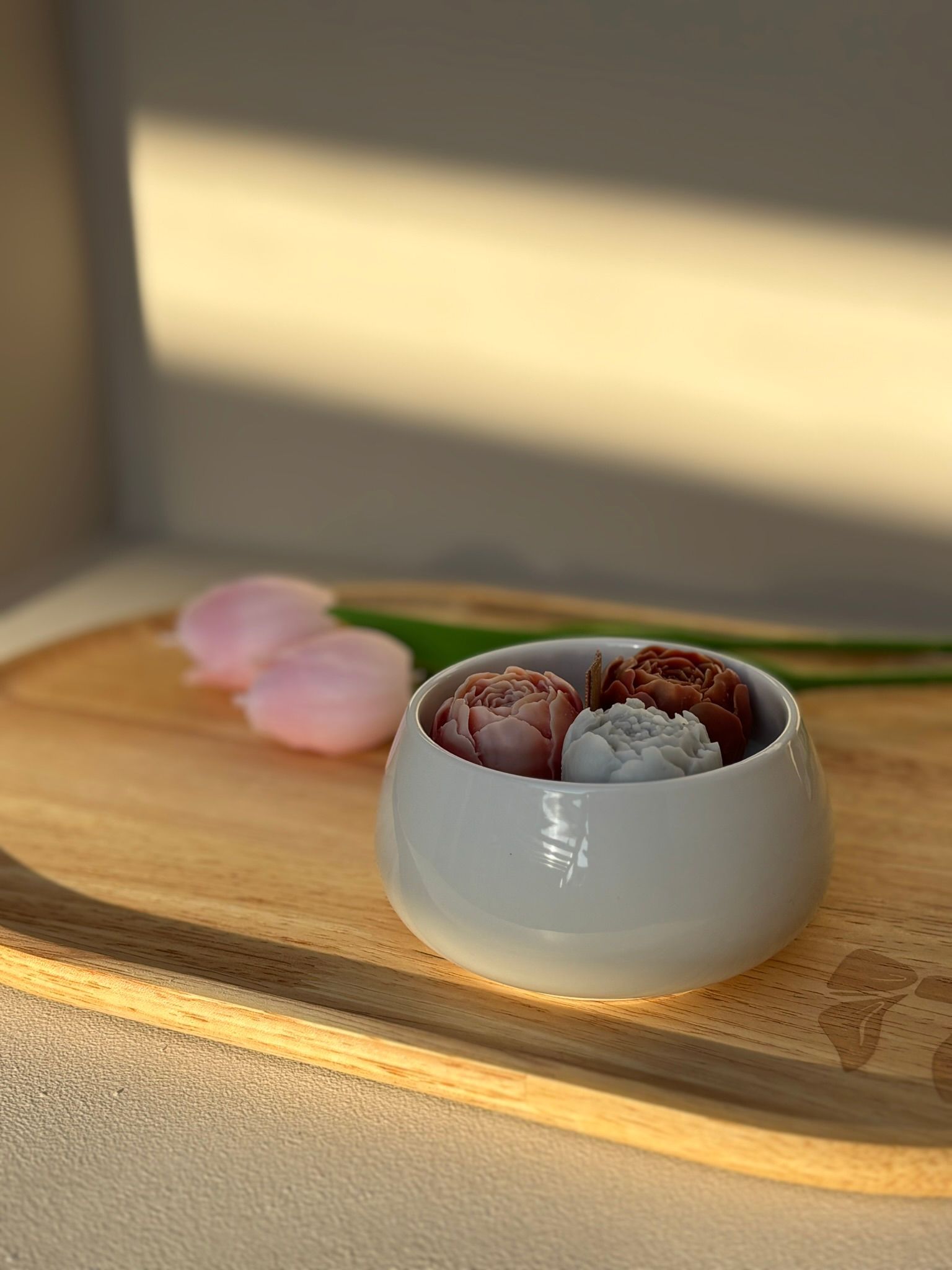 Drie kleine bloemvormige gebakjes in een witte kom op een houten tafel.