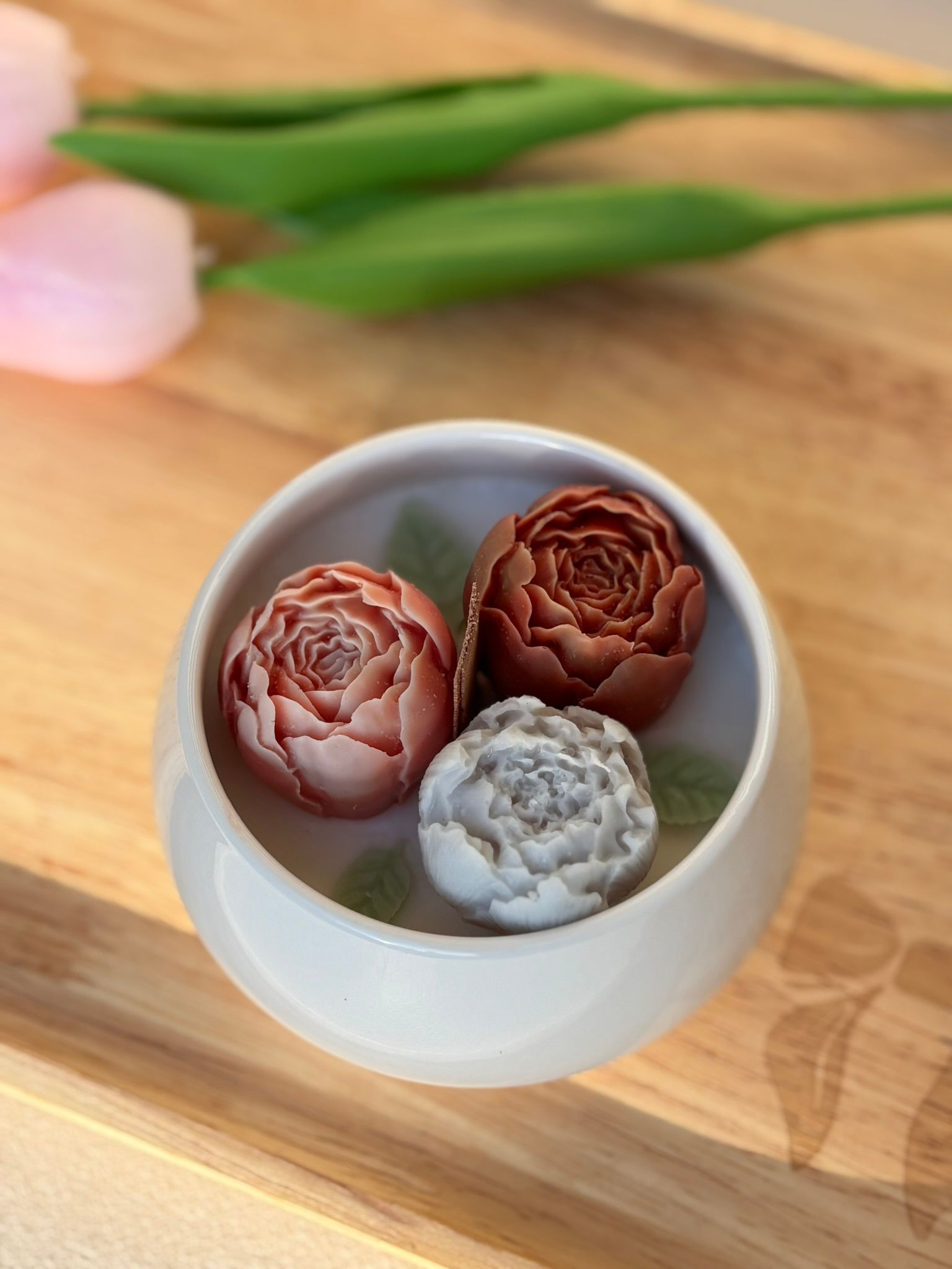 Drie kleine bloemvormige gebakjes in een witte kom op een houten tafel.