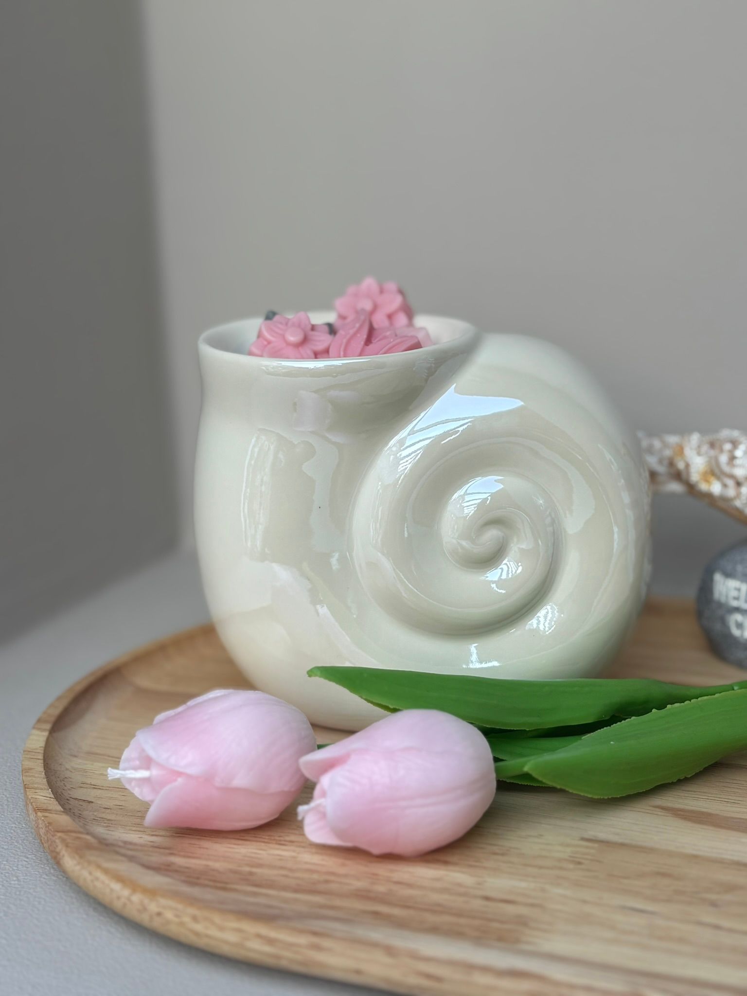 Witte mok met roze bloemvormige snoepjes op een houten ondergrond