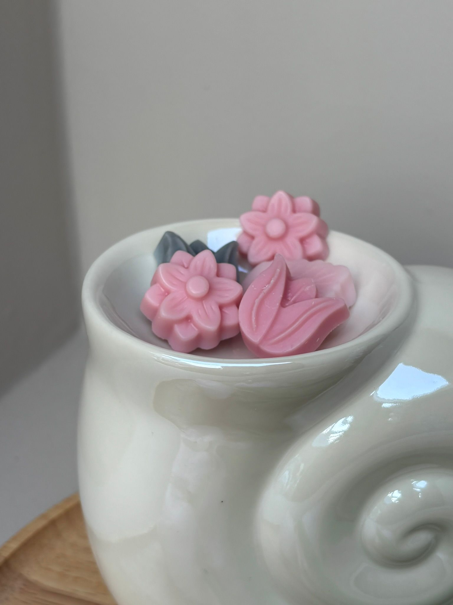 Witte mok met roze bloemvormige snoepjes op een houten ondergrond