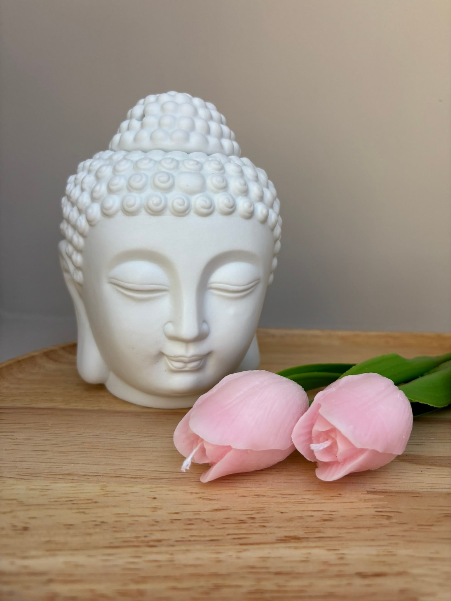 Witte Boeddha-hoofdsculptuur met roze bloemen op een houten ondergrond