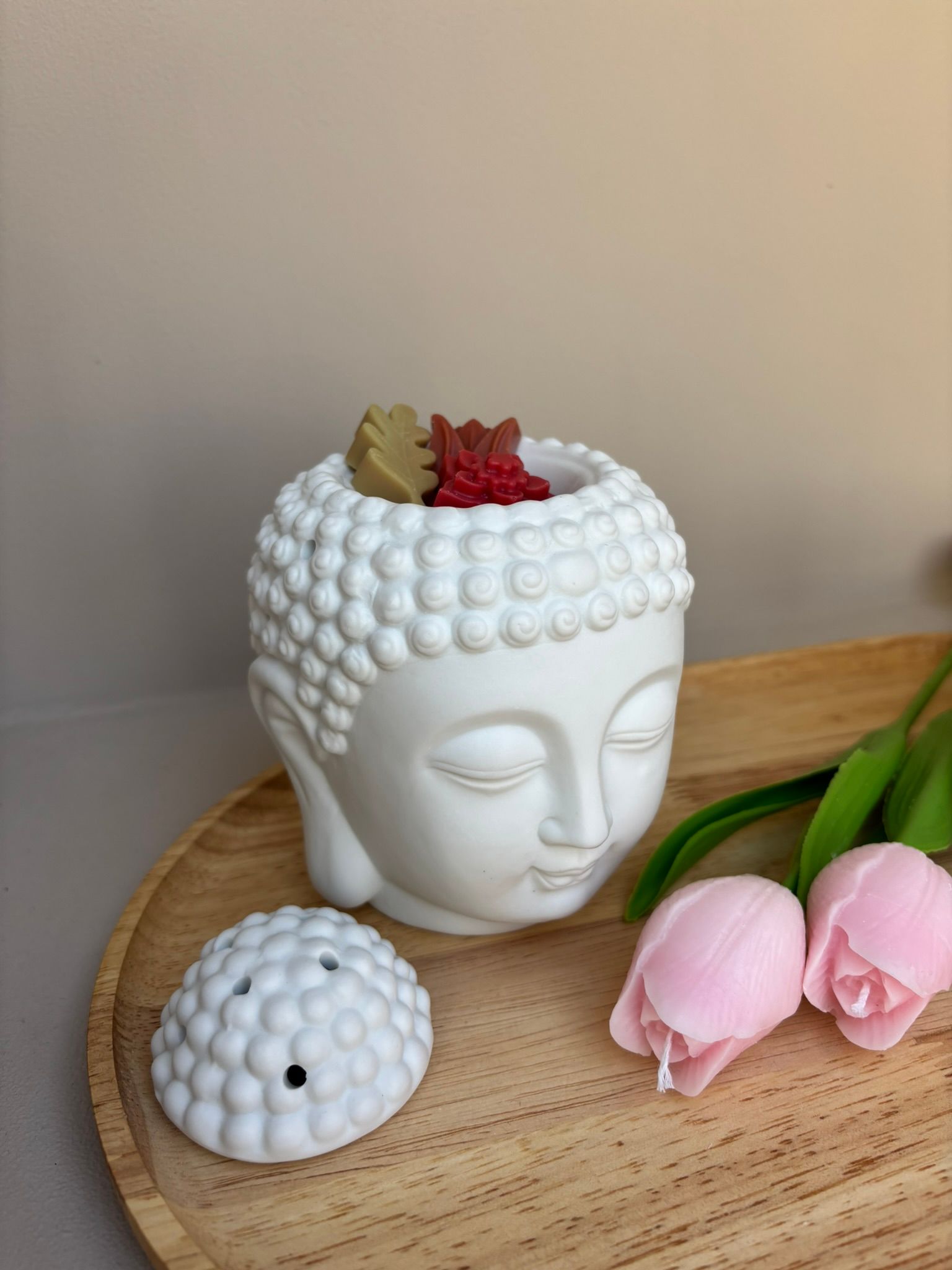 Witte Boeddha-hoofdsculptuur met roze bloemen op een houten ondergrond