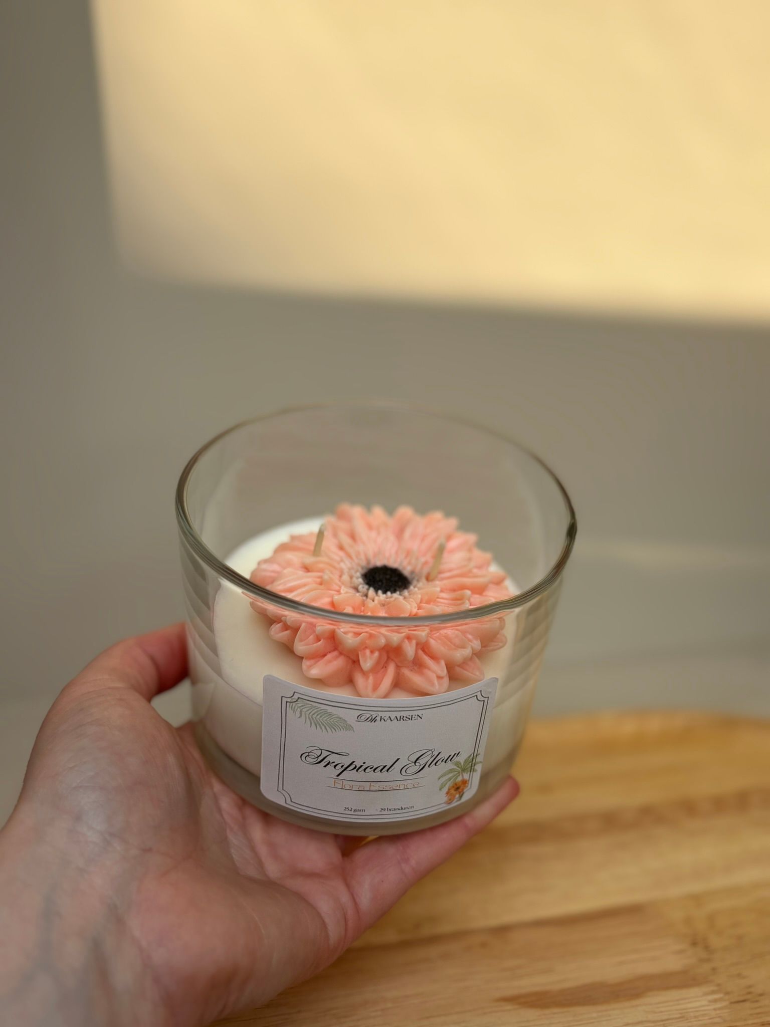 Drie decoratieve kaarsen in glazen potjes op een houten dienblad, met roze, rode en witte was.