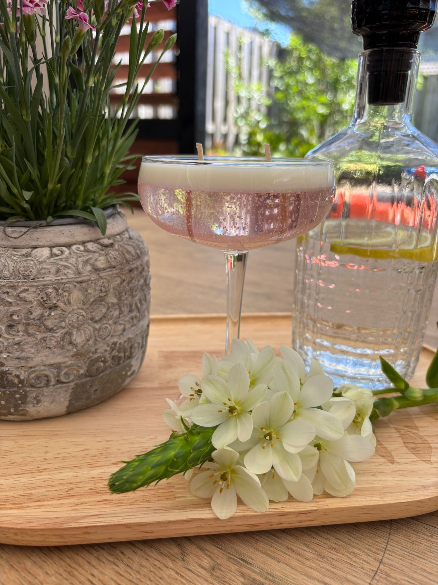 Een cocktail en citroenen op een houten dienblad met een fles citrusdrank en een roze martiniglas.