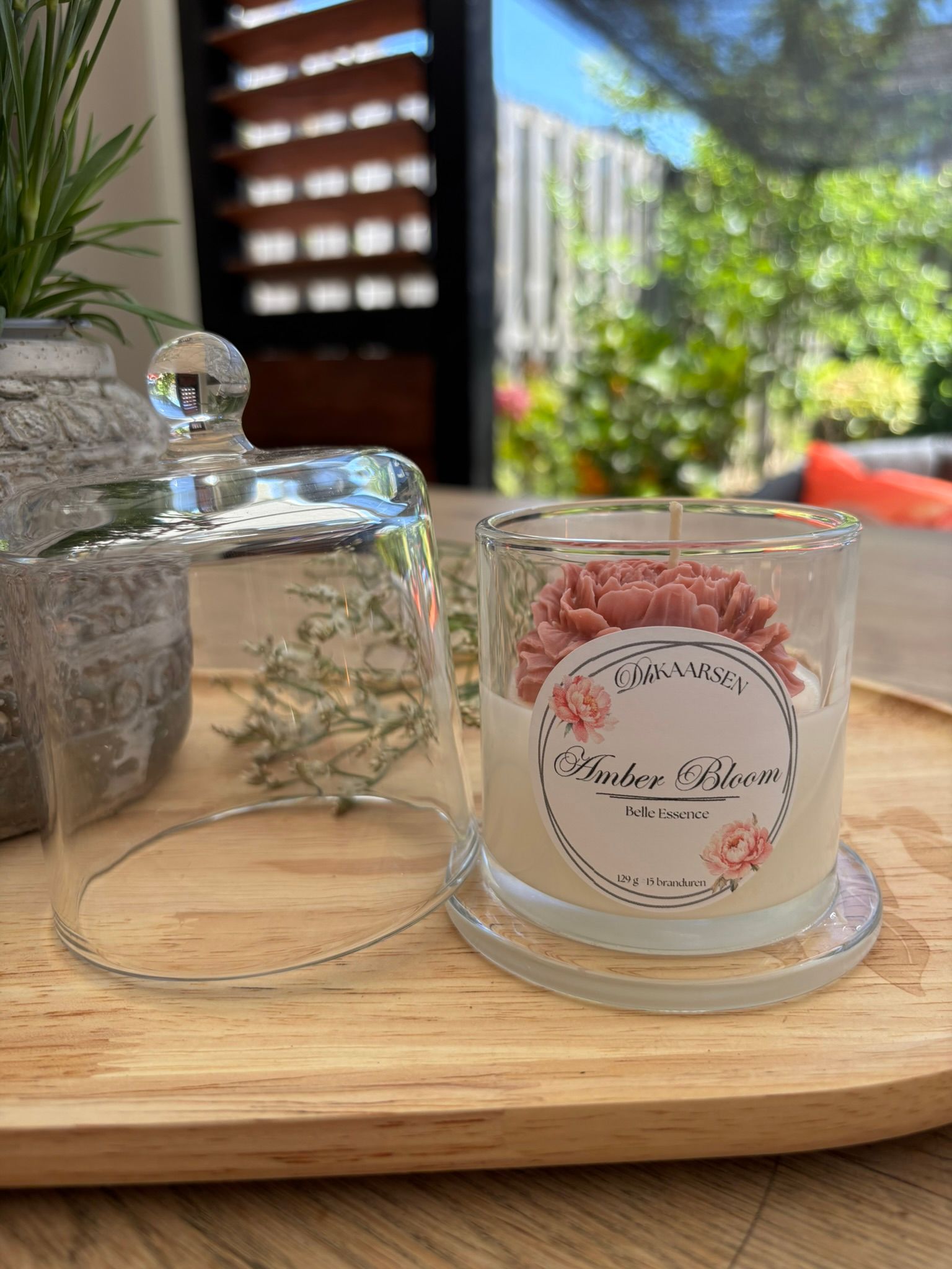 Glazen potjes op een houten dienblad, waaronder een met roze en witte snoepjes, in een lichte binnenomgeving.
