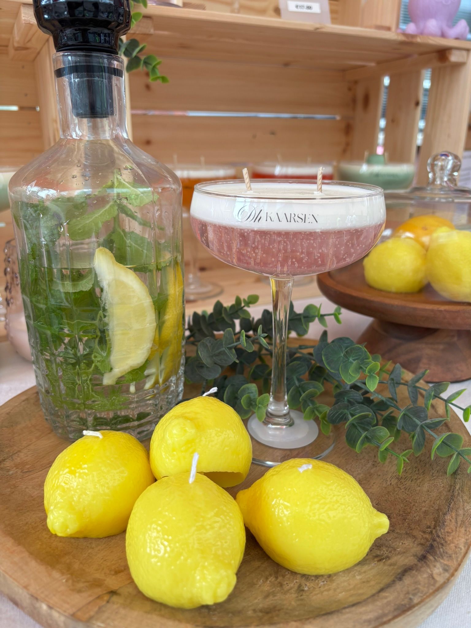 Een cocktail en citroenen op een houten dienblad met een fles citrusdrank en een roze martiniglas.