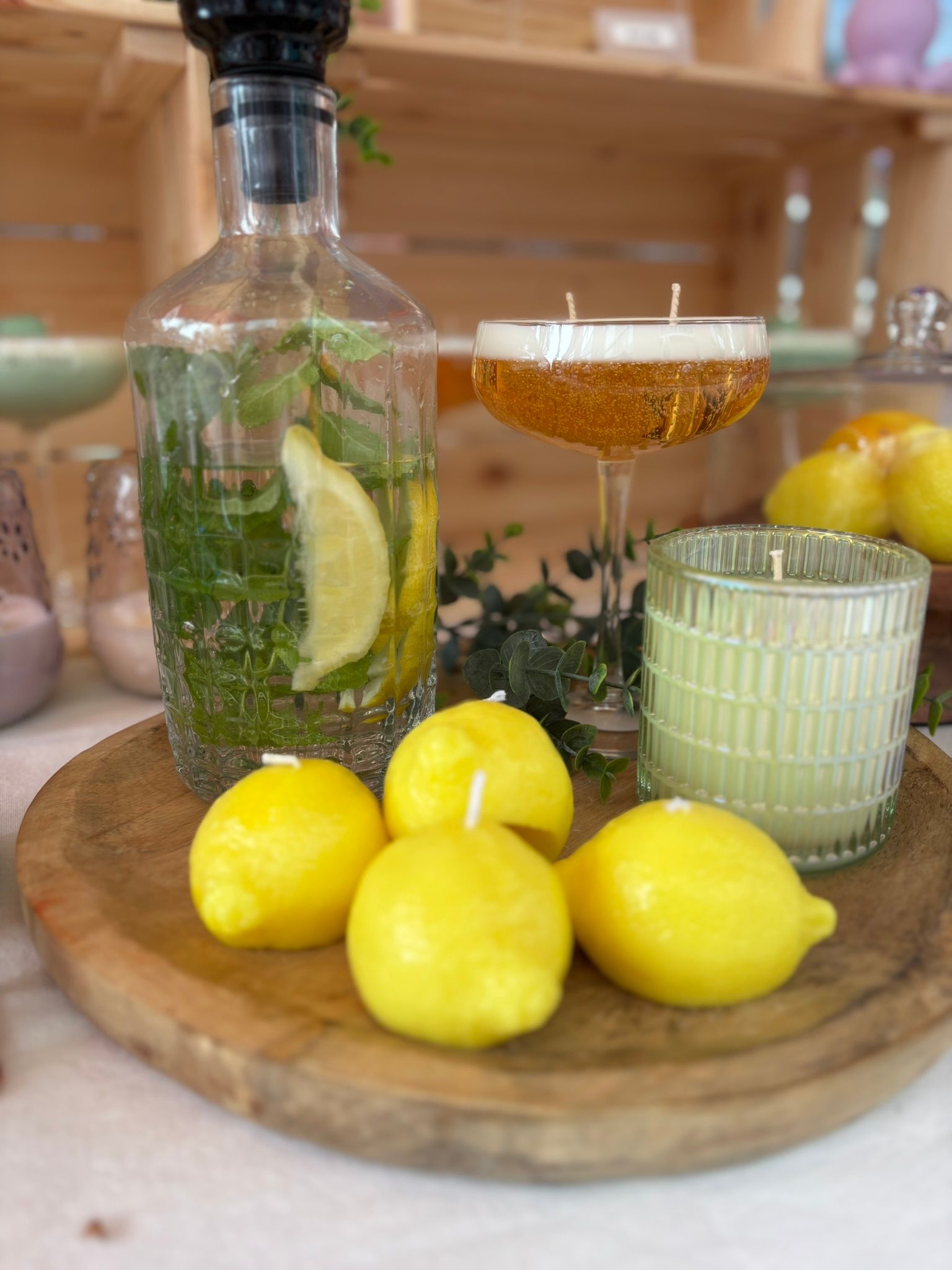 Citroenen op een houten plank naast een glas citrusdrank en een fles met citroenschijfjes en kruiden.