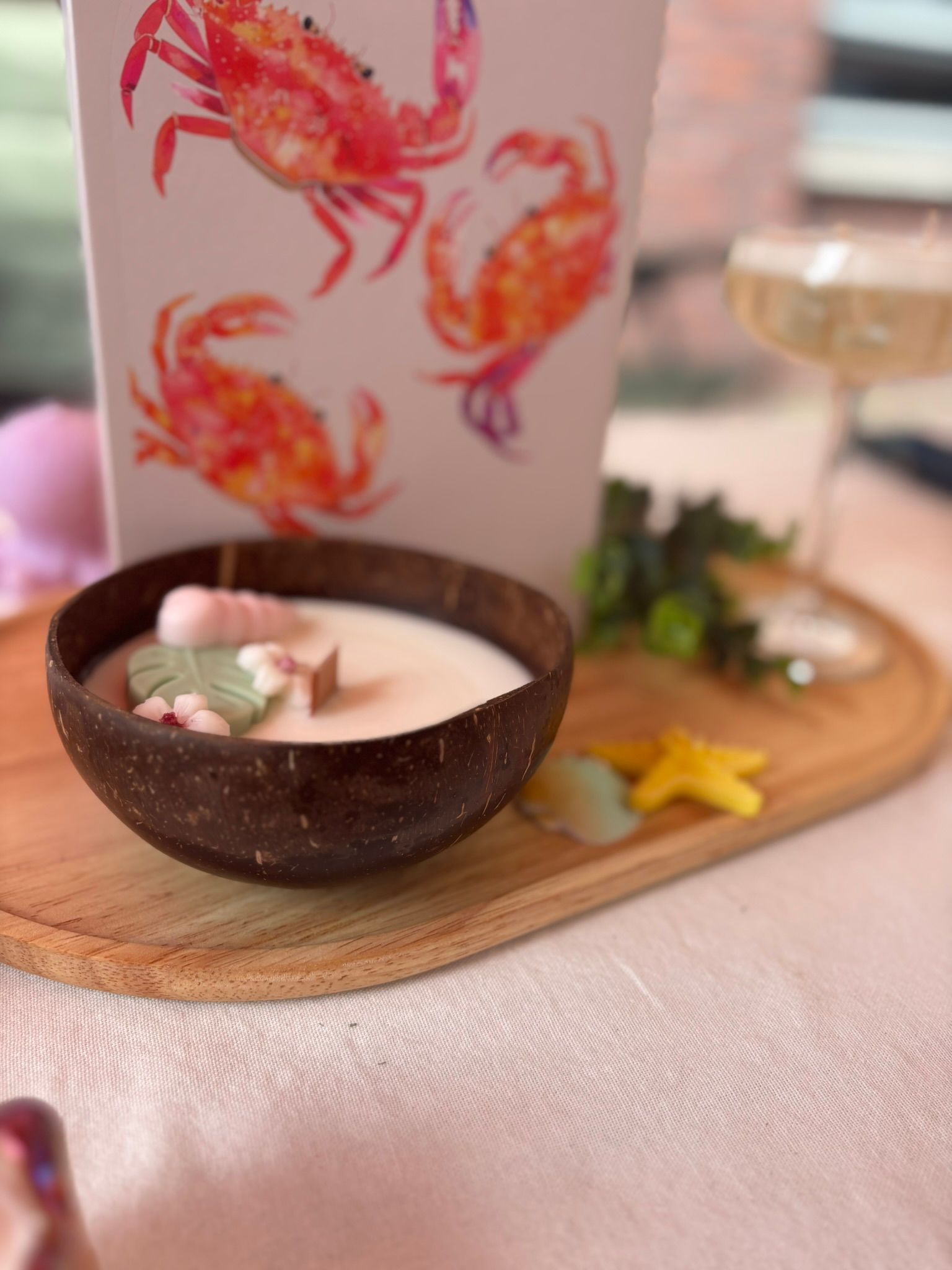 Decoratieve desserttafel met een chocoladekom, een beker met krabmotief en een glas op een houten dienblad.