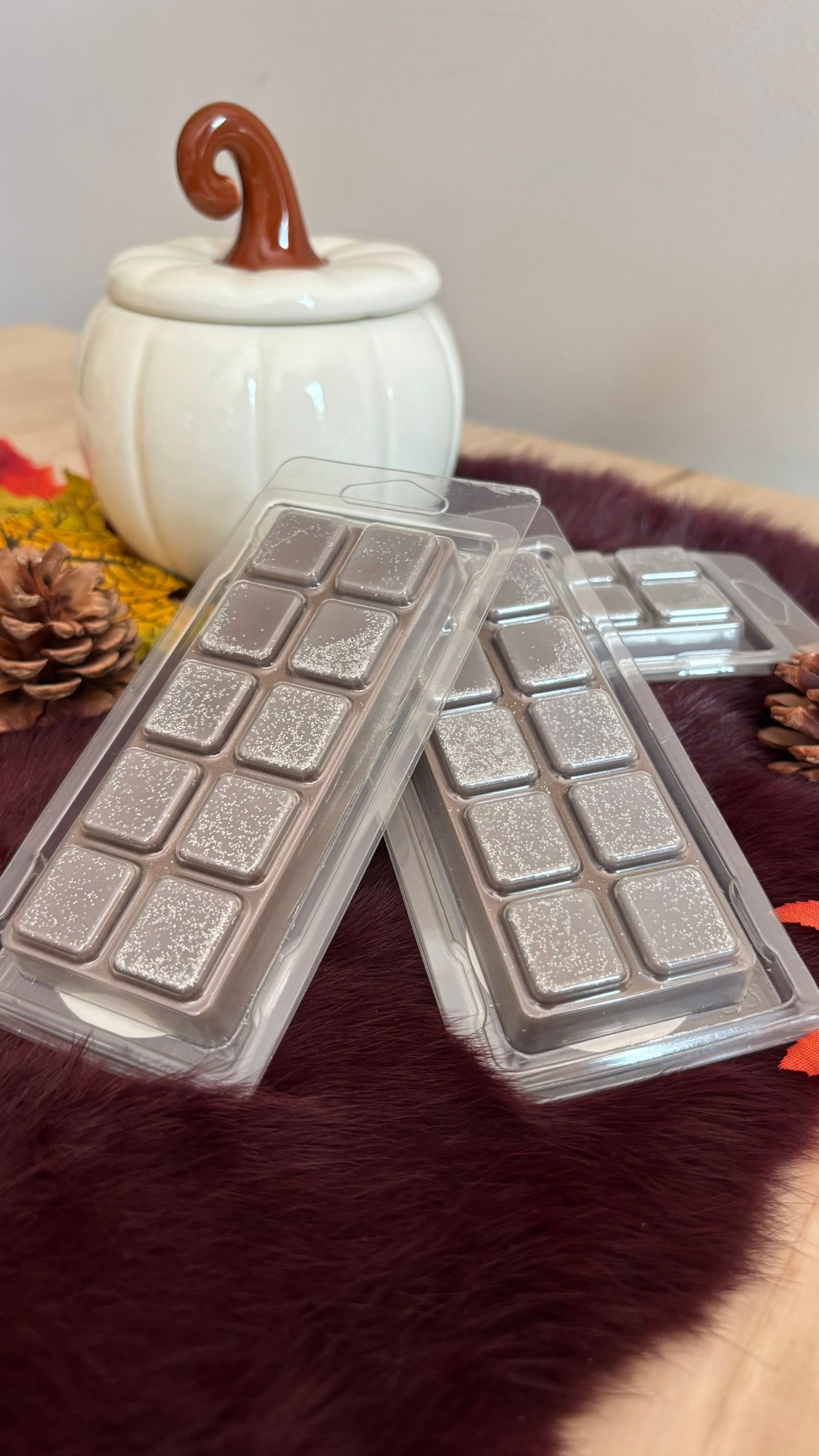 Twee in zilverfolie verpakte chocoladerepen voor een witte keramische pot met een houten lepelhandvat.