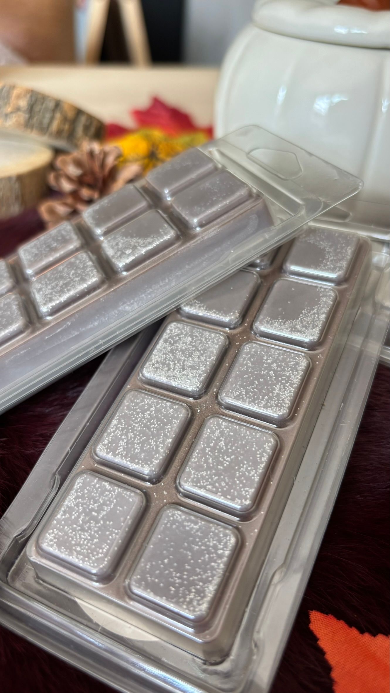 Twee in zilverfolie verpakte chocoladerepen voor een witte keramische pot met een houten lepelhandvat.